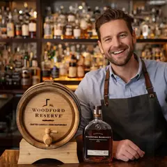 Bartender smiling behind bar with Woodford Reserve bottle and custom oak whiskey aging barrel with wooden spigot on display