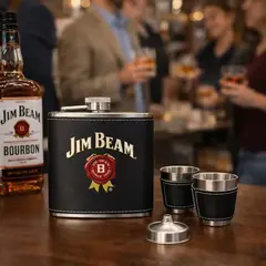 Custom branded flask set with shot glasses on bar during whiskey tasting with guests in background at distillery