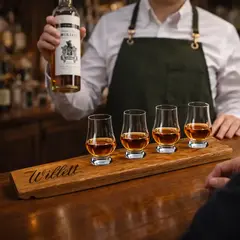 Bartender presenting a custom engraved whiskey flight board with Glencairn glasses filled with bourbon at a tasting bar