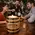 Branded oak barrel candle holder on bar top with bartender and guests, premium distillery promotional product driving brand visibility