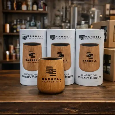 Branded oak whiskey tumblers with custom logo displayed in distillery gift shop as promotional merchandise