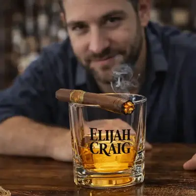 Close-up of whiskey cigar glass with lit cigar resting on top and bourbon inside, man in background, premium bar and distillery promotional product