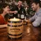 Branded oak barrel candle holder on bar top with bartender and guests, premium distillery promotional product driving brand visibility