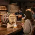 Branded whiskey barrel promotional product in a bar setting pouring bourbon into a glass, with bartender and guests creating a premium brand experience.